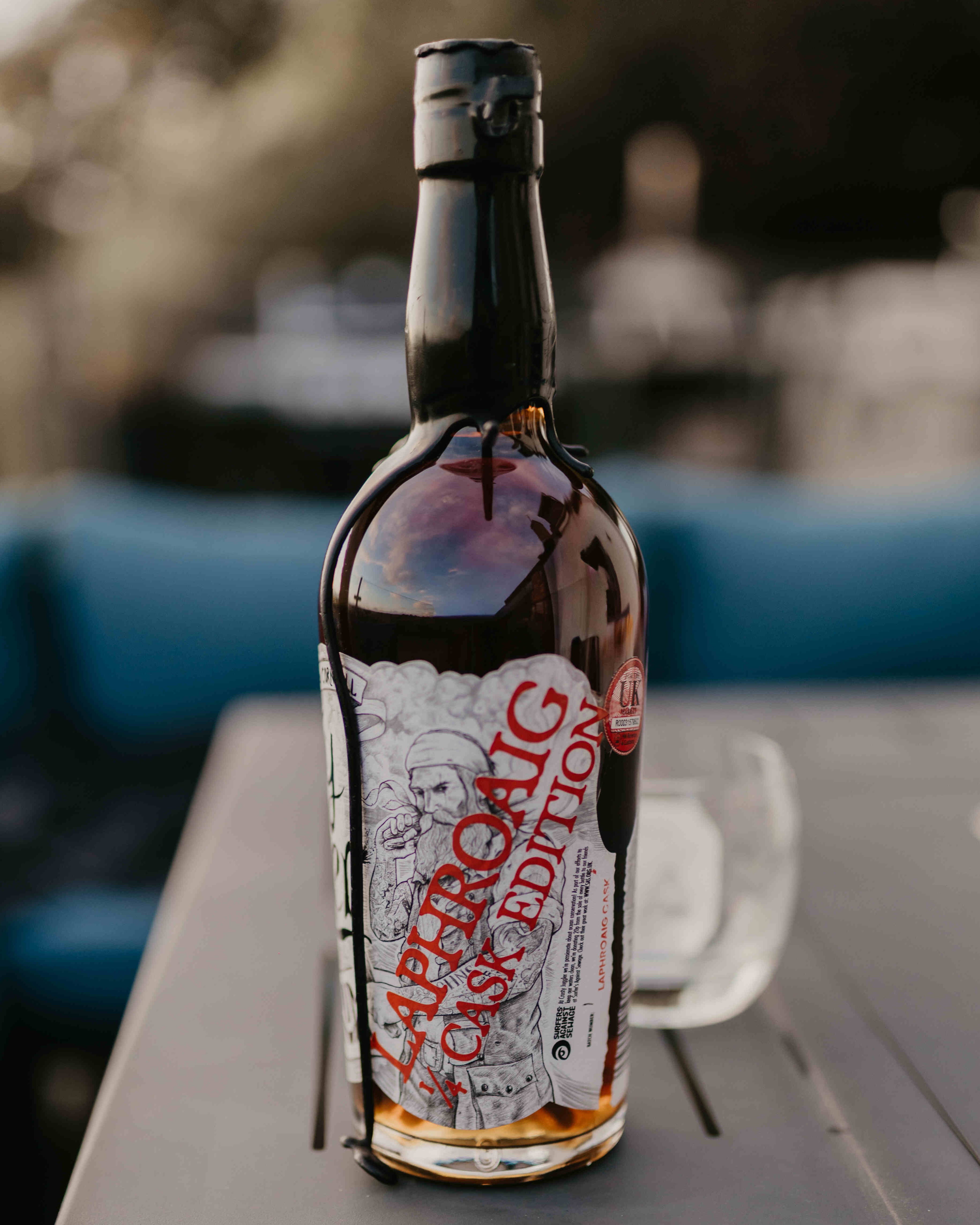 Bottle of Laphroaig Cask Edition rum on a table with a blurred outdoor background