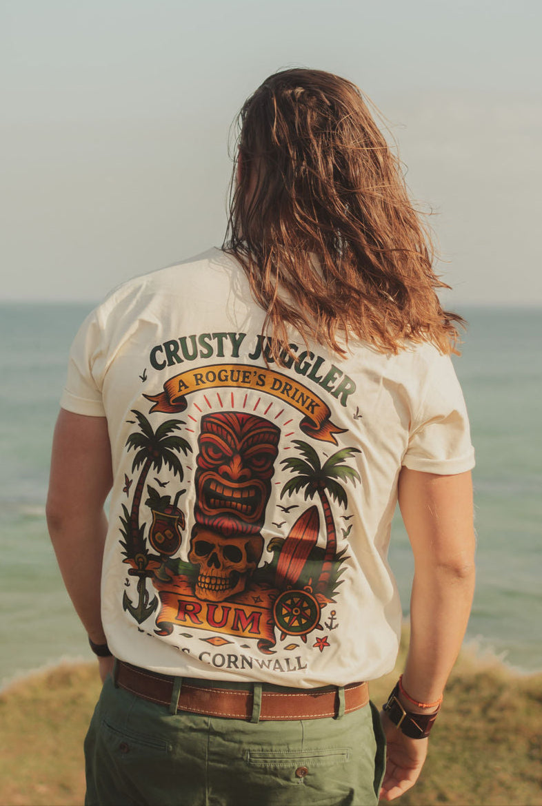 Person wearing a 'Crusty Juggler Rum' t-shirt by the ocean